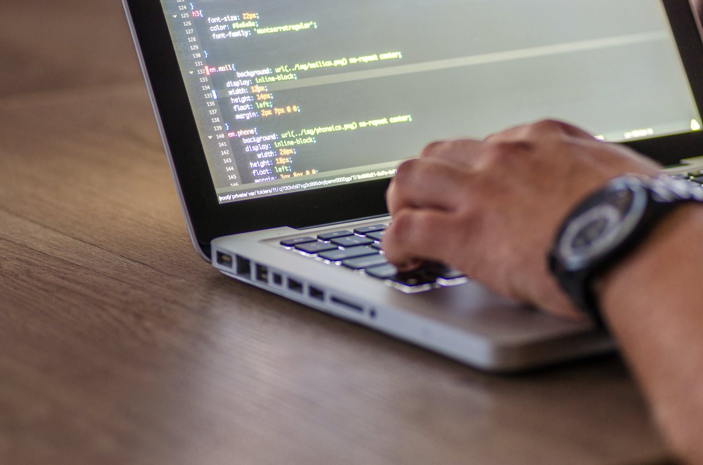 Photo of person using a laptop to write CSS code.